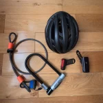 Cycling gear: helmet, locks, accessories laid out on a wooden floor.