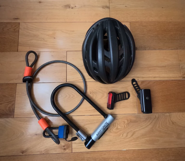 Cycling gear: helmet, locks, accessories laid out on a wooden floor.