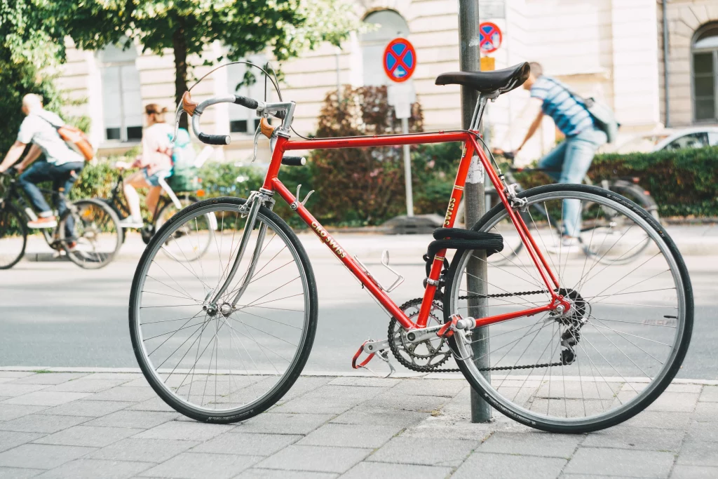 Red bike parked by lamp post and locked