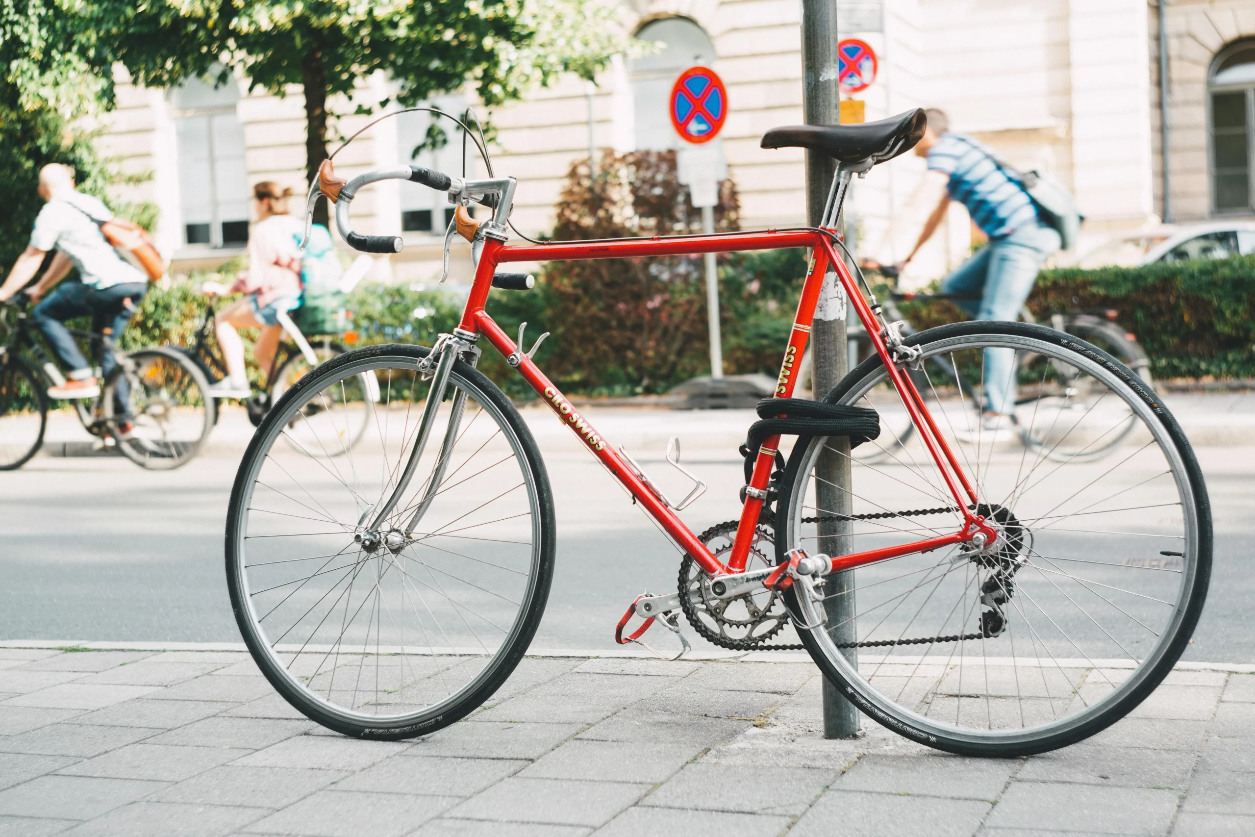 Red bike parked by lamp post and locked