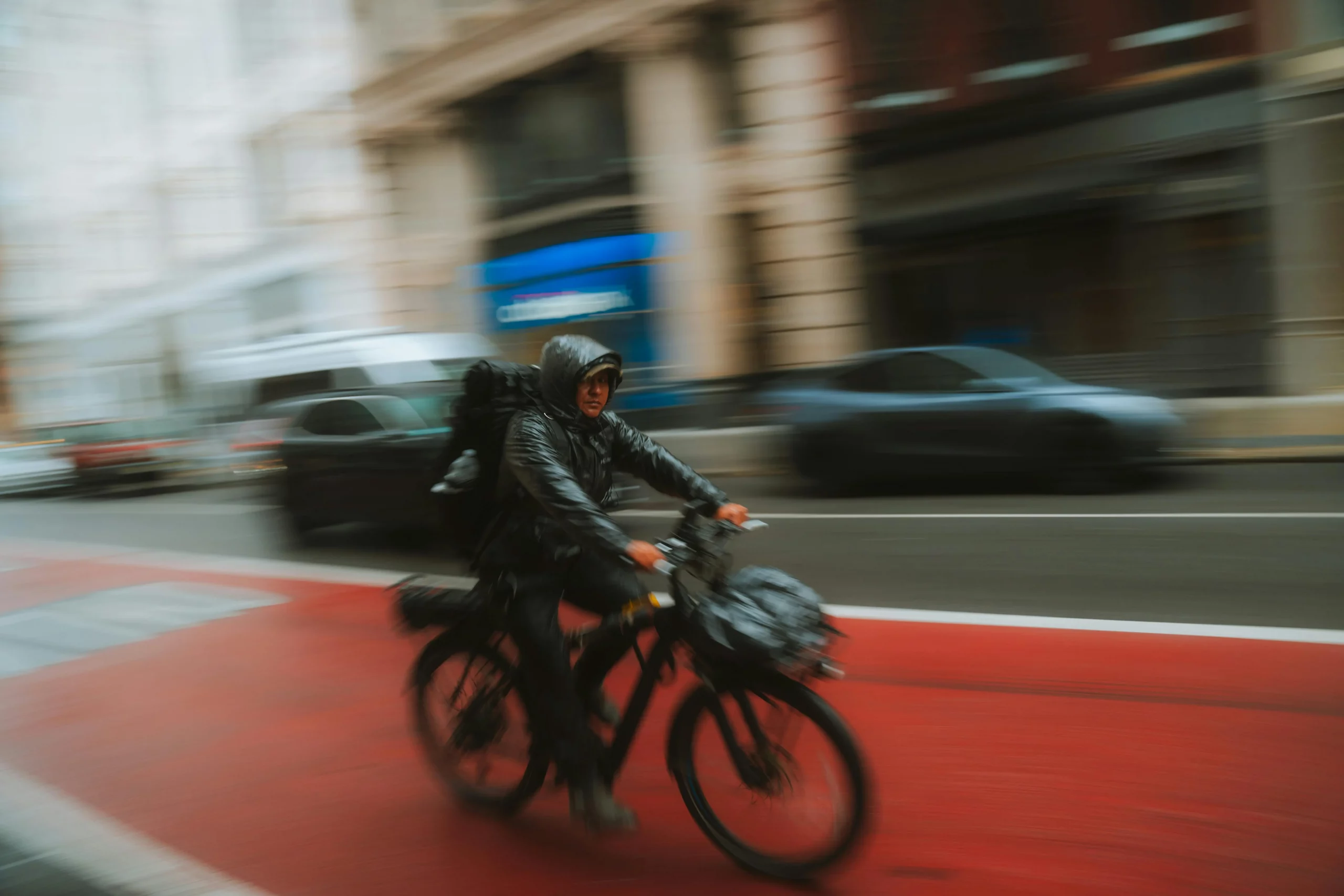 Cyclist on rainy day in rain jacket on a red bike lane