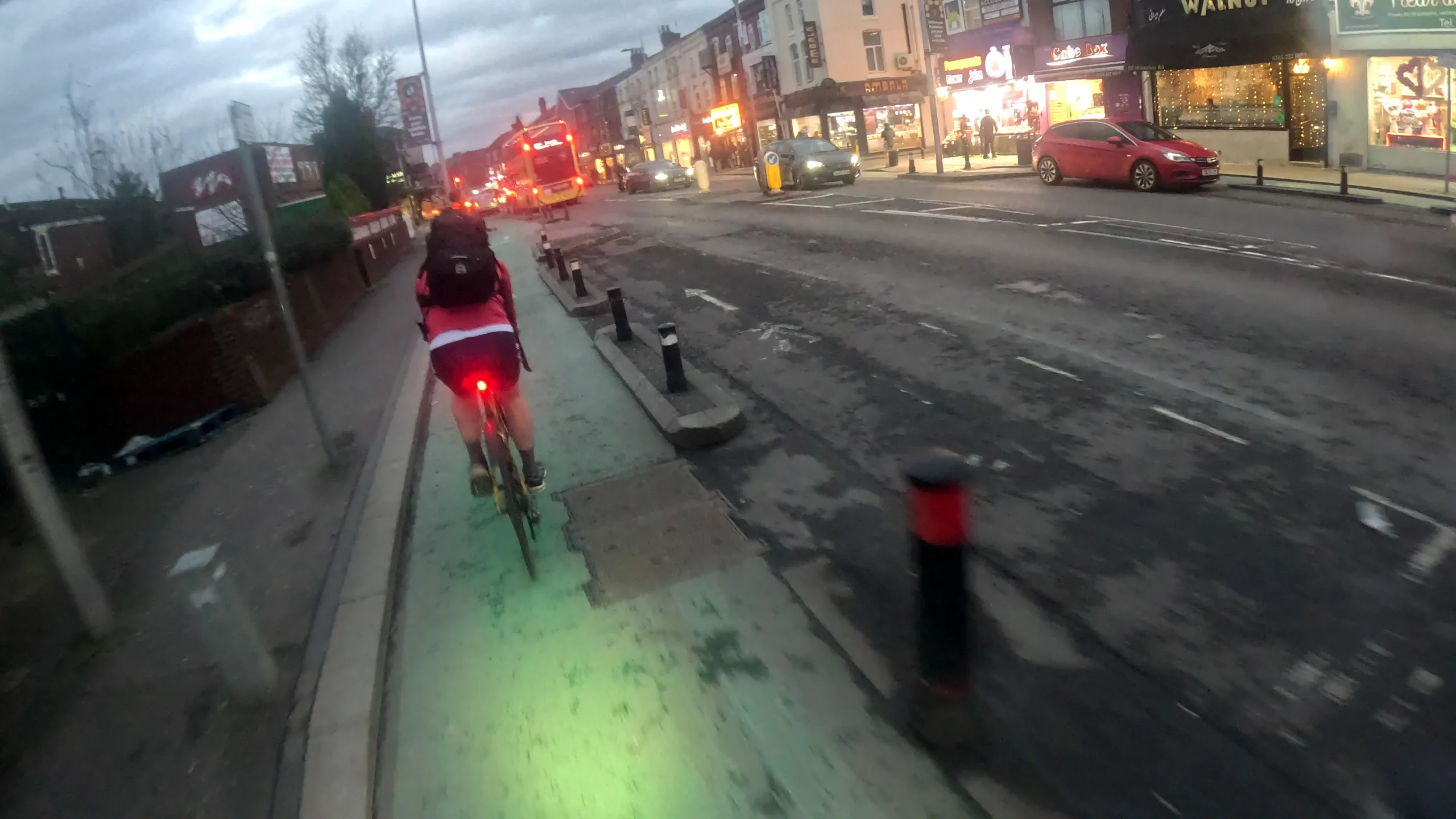 A cyclists on a cycle lane at dawn with a rear red light