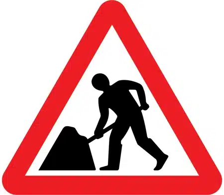 A red triangle sign with a black man digging a pile of dirt